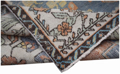 A folded vintage Persian rug featuring intricate floral patterns in blue, orange, and cream tones.
