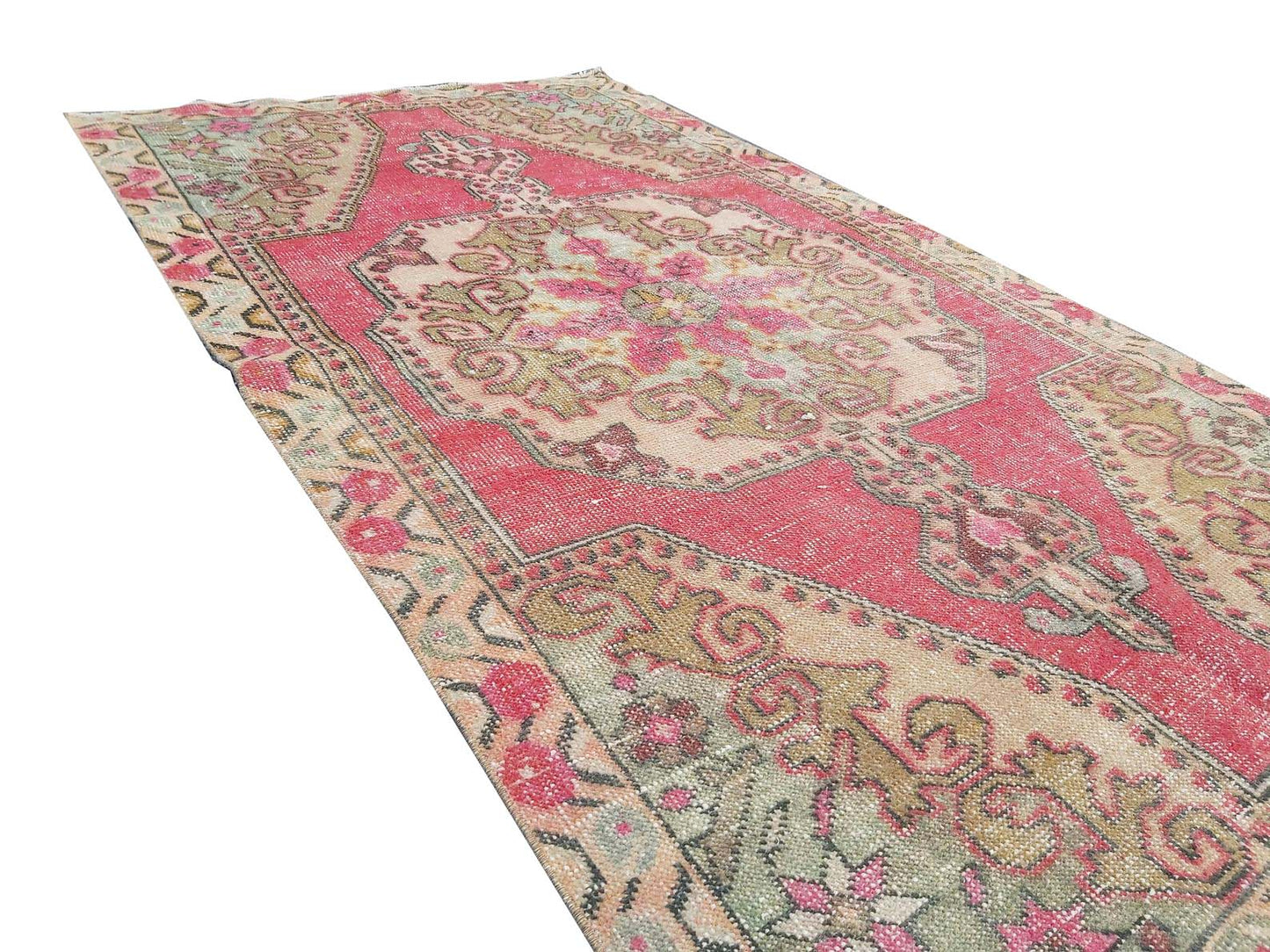 A vintage handmade Turkish wool rug featuring a central floral medallion in shades of pink and beige.