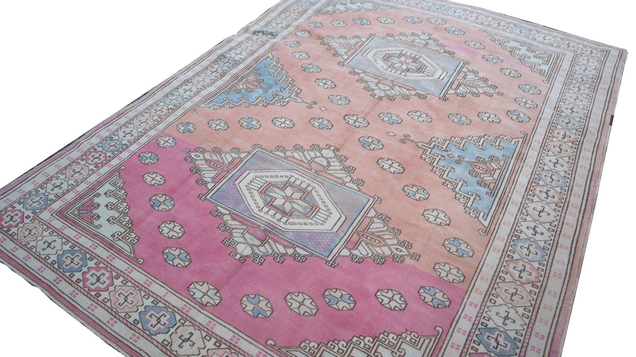 A vintage handmade Turkish Anatolian rug featuring a geometric tribal pattern in pink and blue tones.