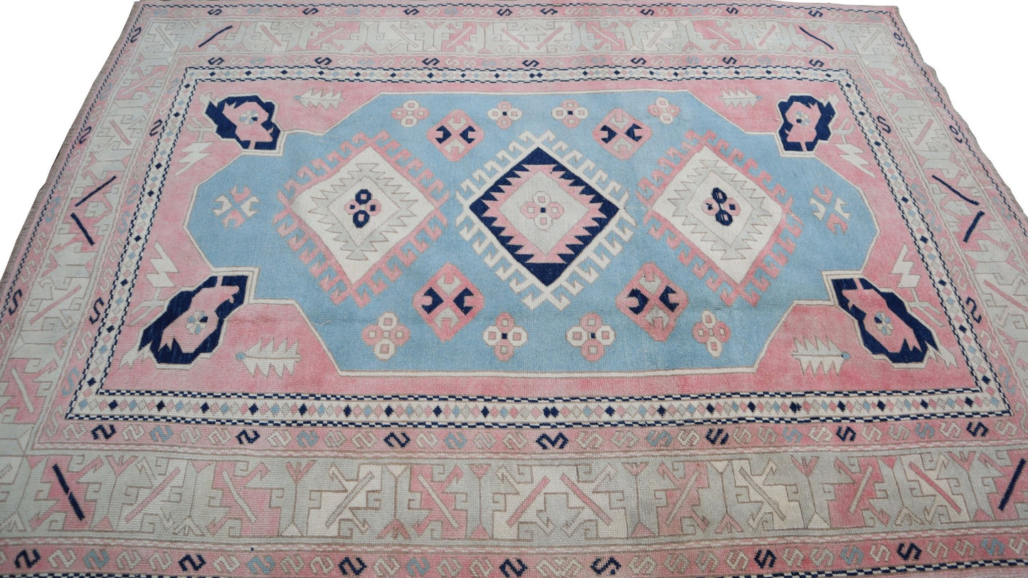 Vintage Turkish Oushak rug featuring a geometric pattern in shades of blue, pink, and cream.