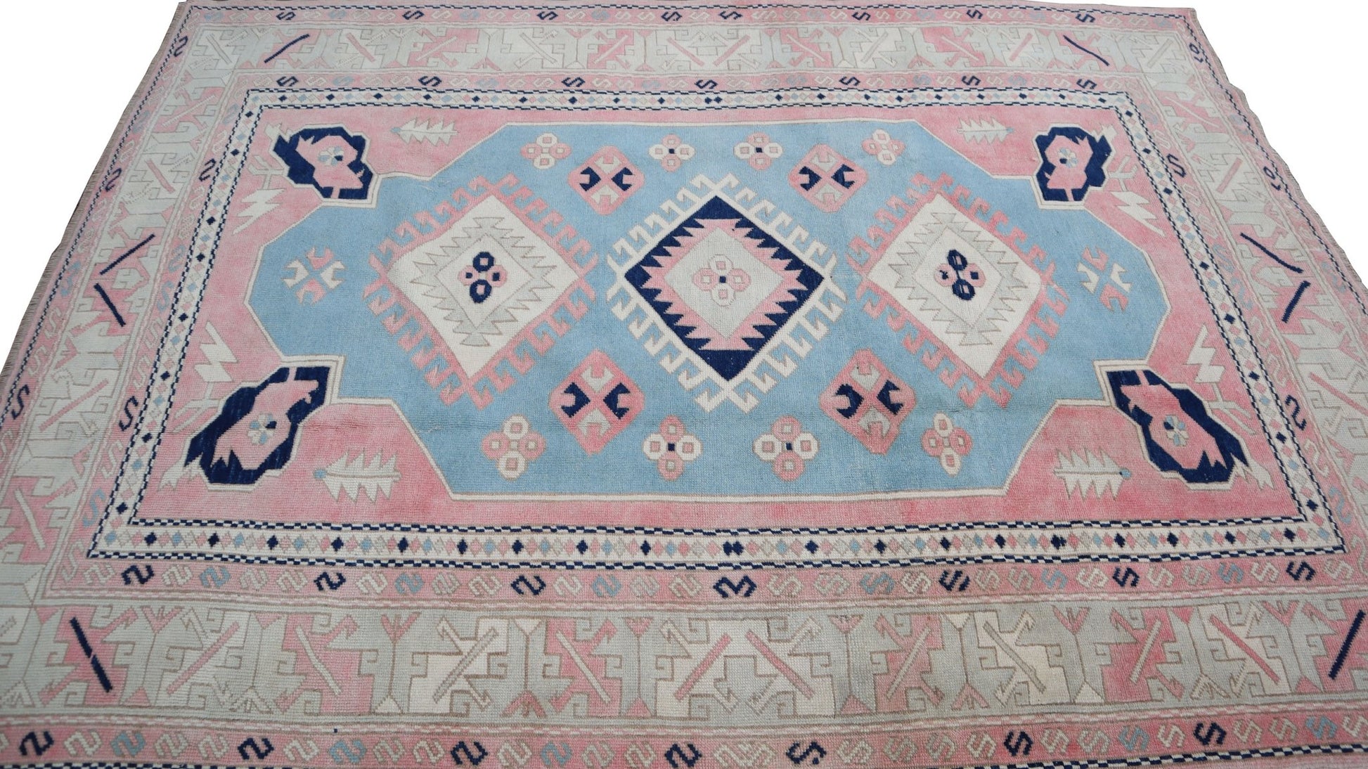 Vintage Turkish Oushak rug featuring a geometric pattern in shades of blue, pink, and cream.