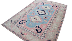 A vintage handmade Turkish Oushak rug featuring a traditional geometric pattern in blue and pink.