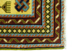 A corner view of a vintage Turkish runner featuring geometric patterns in yellow, blue, and red.
