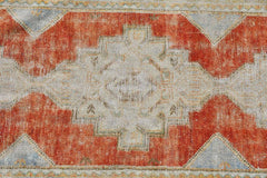 A vintage Turkish runner featuring a geometric central medallion in orange and light grey tones.