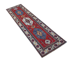 A handwoven vintage Turkish runner rug featuring geometric medallions on a red field.