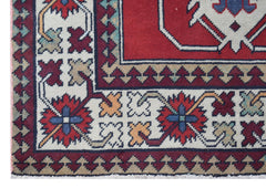 A vintage Turkish runner featuring a geometric floral pattern in red, blue, and cream tones.