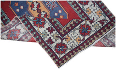 A handwoven vintage Turkish runner featuring a geometric floral pattern in red, blue, and cream.