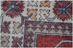 A close-up of a vintage Turkish runner featuring geometric floral motifs in red, blue, and tan.