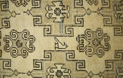 A vintage handmade runner rug featuring a geometric pattern with a small bird motif in beige tones.