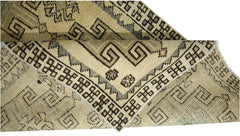 A folded vintage Turkish Anatolian runner featuring geometric patterns in beige and brown tones.