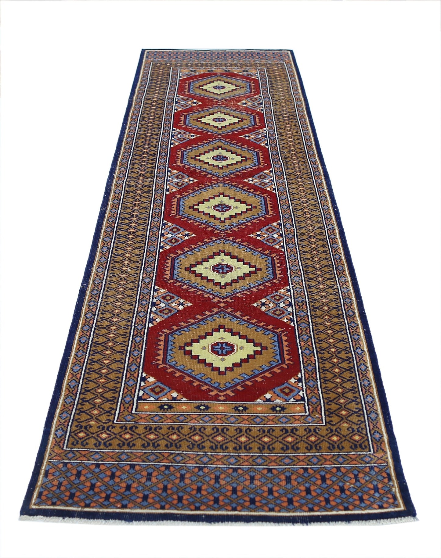 A vintage handmade wool runner featuring repeating geometric diamond motifs in red and tan.