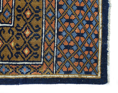 A vintage handmade wool runner featuring a geometric Bokhara pattern in blue, orange, and brown.