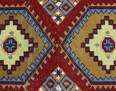 A vintage handmade wool runner featuring a geometric pattern of diamonds in red, gold, and blue.