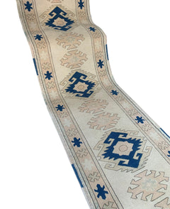 A vintage Turkish Oushak runner featuring blue and beige geometric tribal motifs on a wool base.