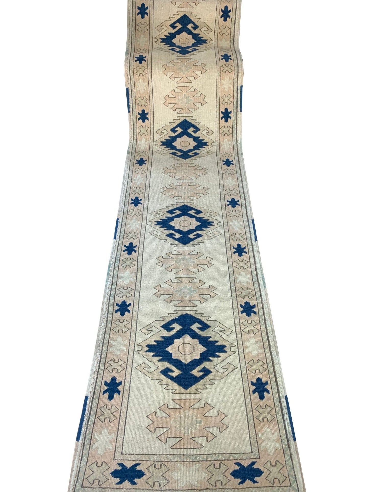 A vintage Turkish Oushak runner featuring blue geometric tribal motifs on a cream background.