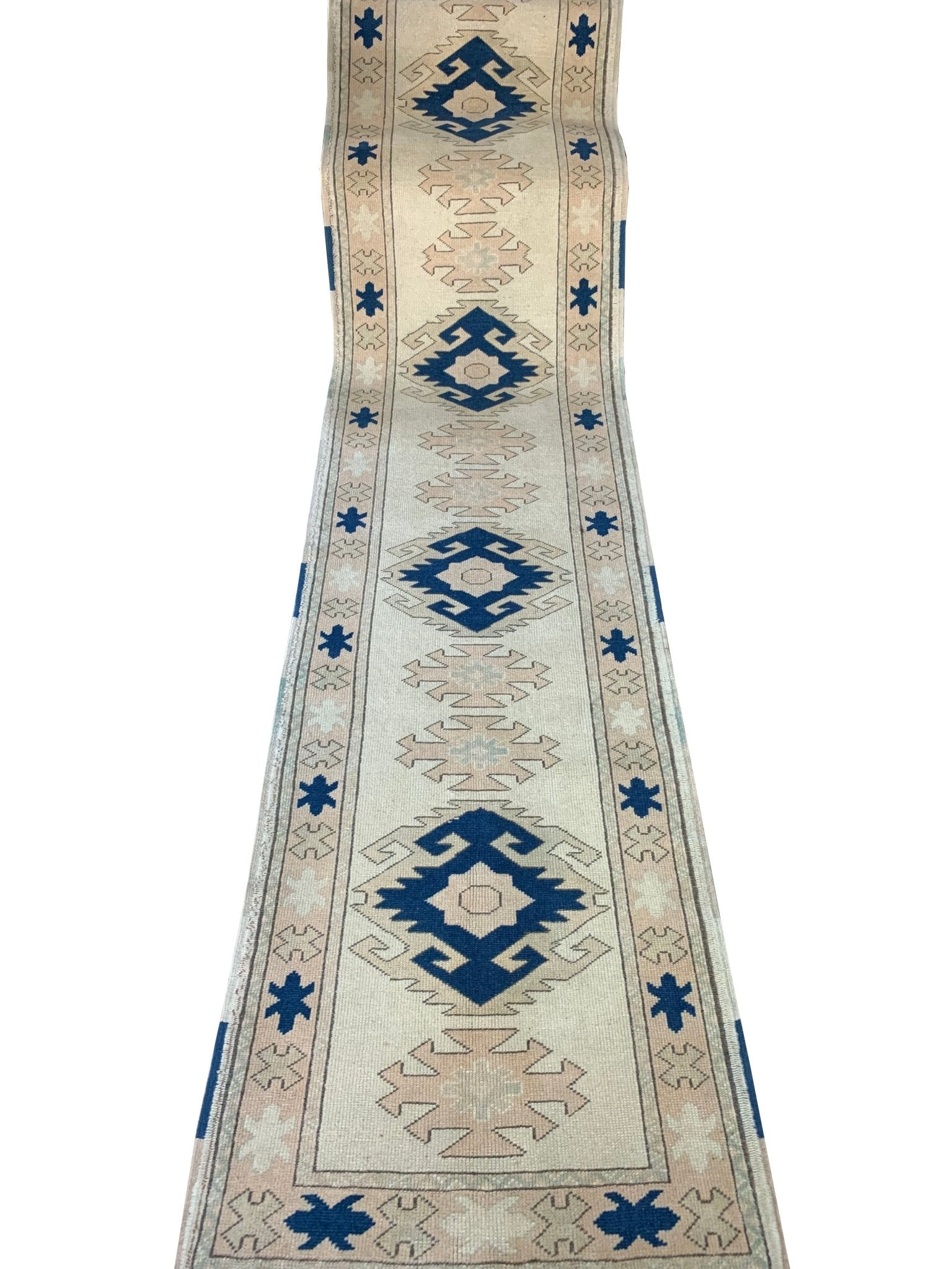 A vintage Turkish Oushak runner featuring blue geometric tribal motifs on a cream background.