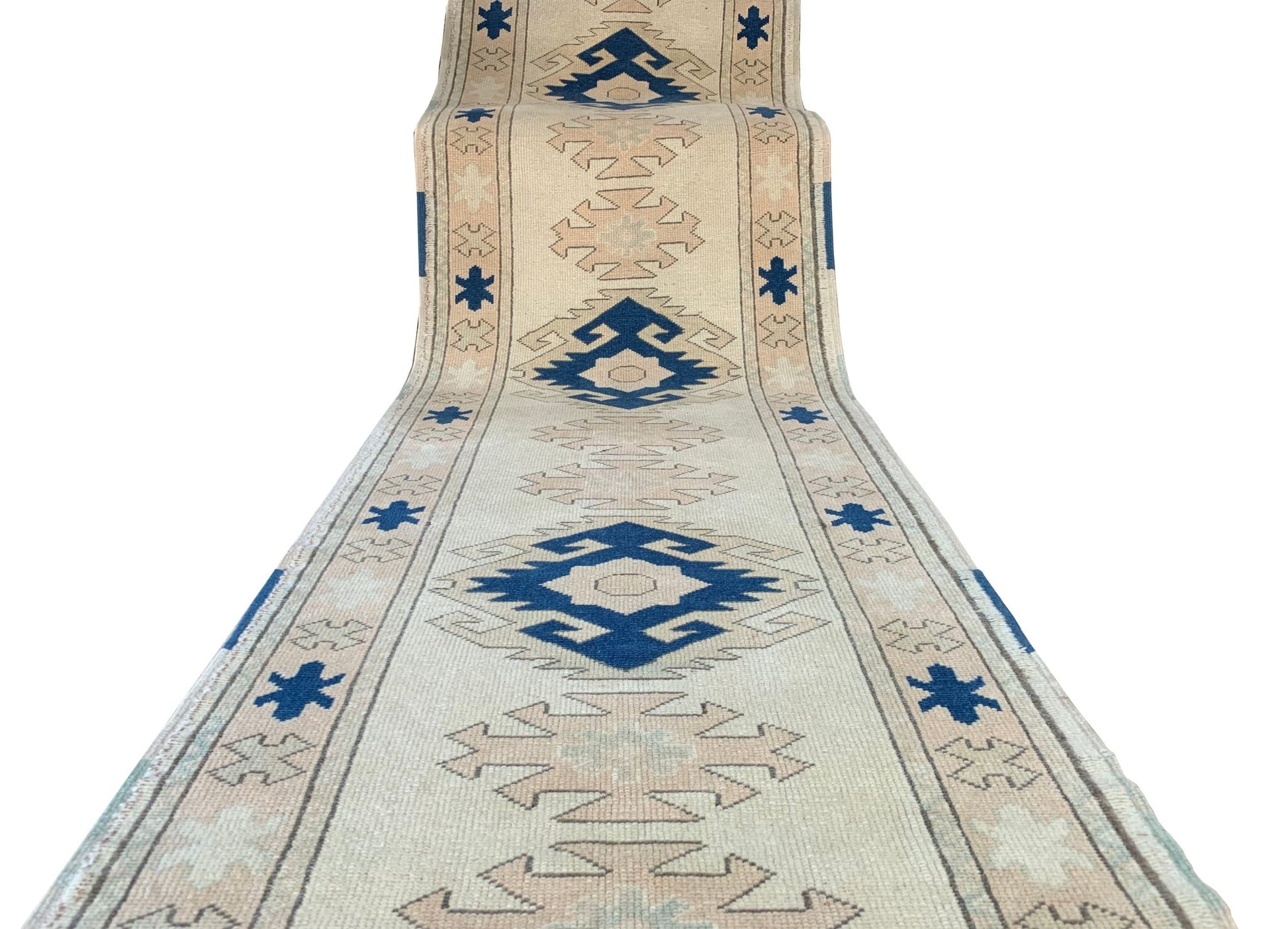 A vintage Turkish Oushak runner featuring tribal blue and beige geometric motifs on a wool base.