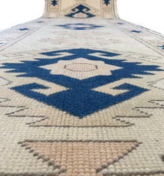 A vintage Turkish Oushak runner featuring blue tribal Seljuk motifs on a cream wool background.
