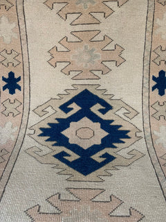 A vintage Turkish Oushak runner featuring geometric tribal motifs in blue and beige wool.