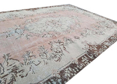 A vintage Turkish Isparta rug featuring a faded floral medallion in soft pink and brown tones.