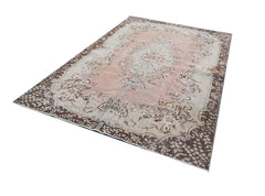 A vintage Turkish Isparta rug featuring a soft pink central floral medallion and dark brown borders.