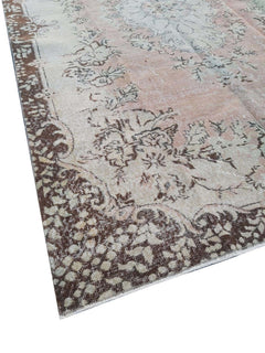 A vintage Turkish Isparta rug featuring a soft floral center and a dark brown patterned border.