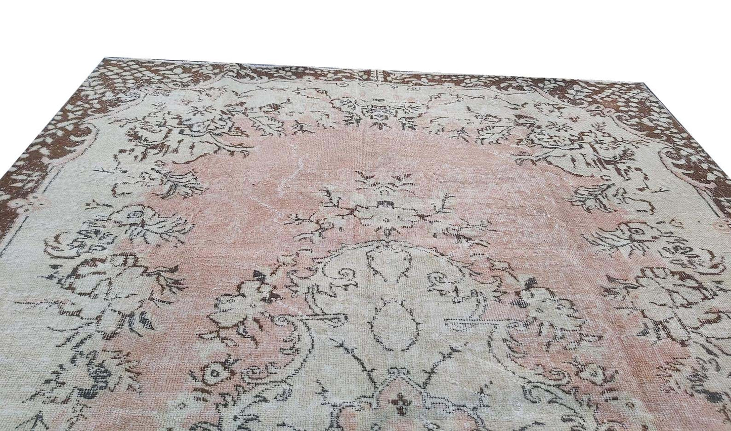 A vintage handmade Turkish Isparta rug featuring a soft pink floral center and a dark brown border.