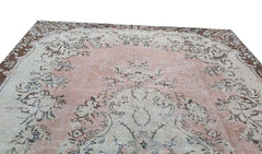 A vintage handmade Turkish Isparta rug featuring a soft pink floral center and a dark brown border.