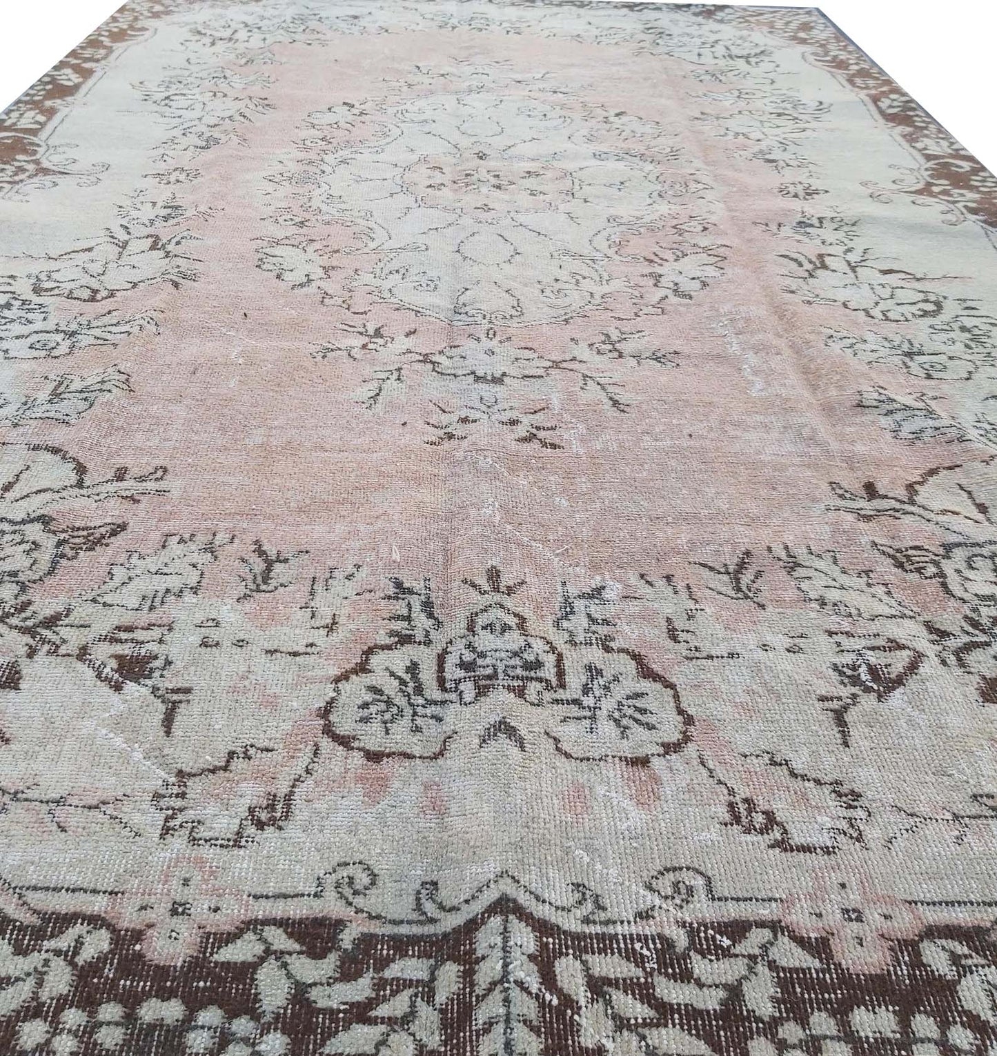 A vintage Turkish Isparta rug featuring a floral medallion design in soft pink and brown tones.