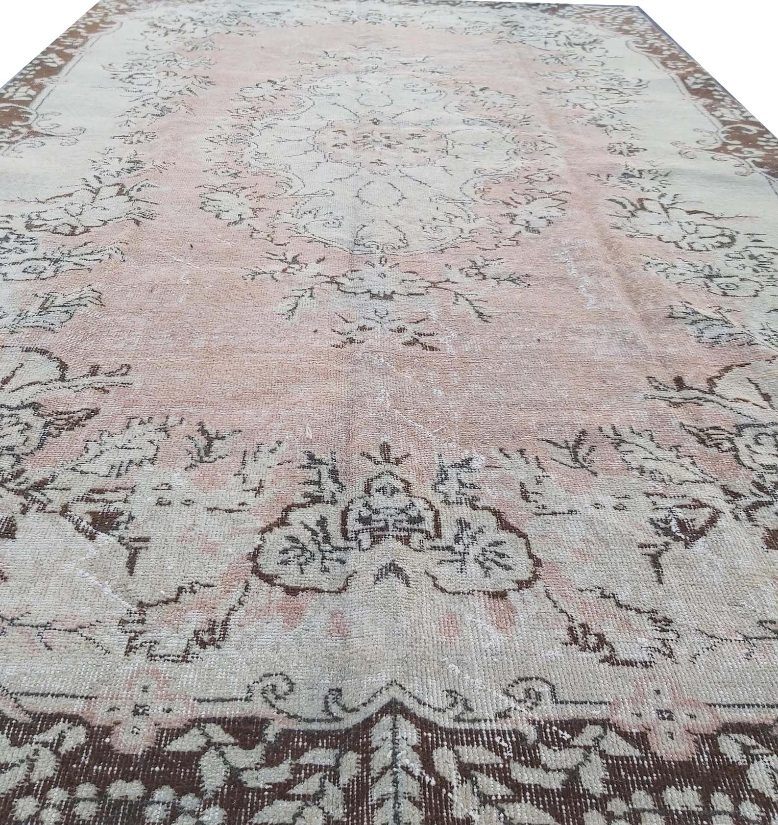 A vintage Turkish Isparta rug featuring a floral medallion design in soft pink and brown tones.