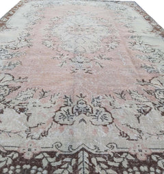 A vintage Turkish Isparta rug featuring a floral medallion design in soft pink and brown tones.