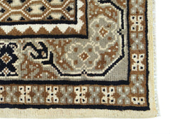 A close-up of a handwoven Afghan rug featuring geometric tribal patterns in brown and cream wool.