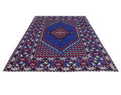 A vintage handmade Turkish rug featuring a central medallion on a deep blue field with red accents.