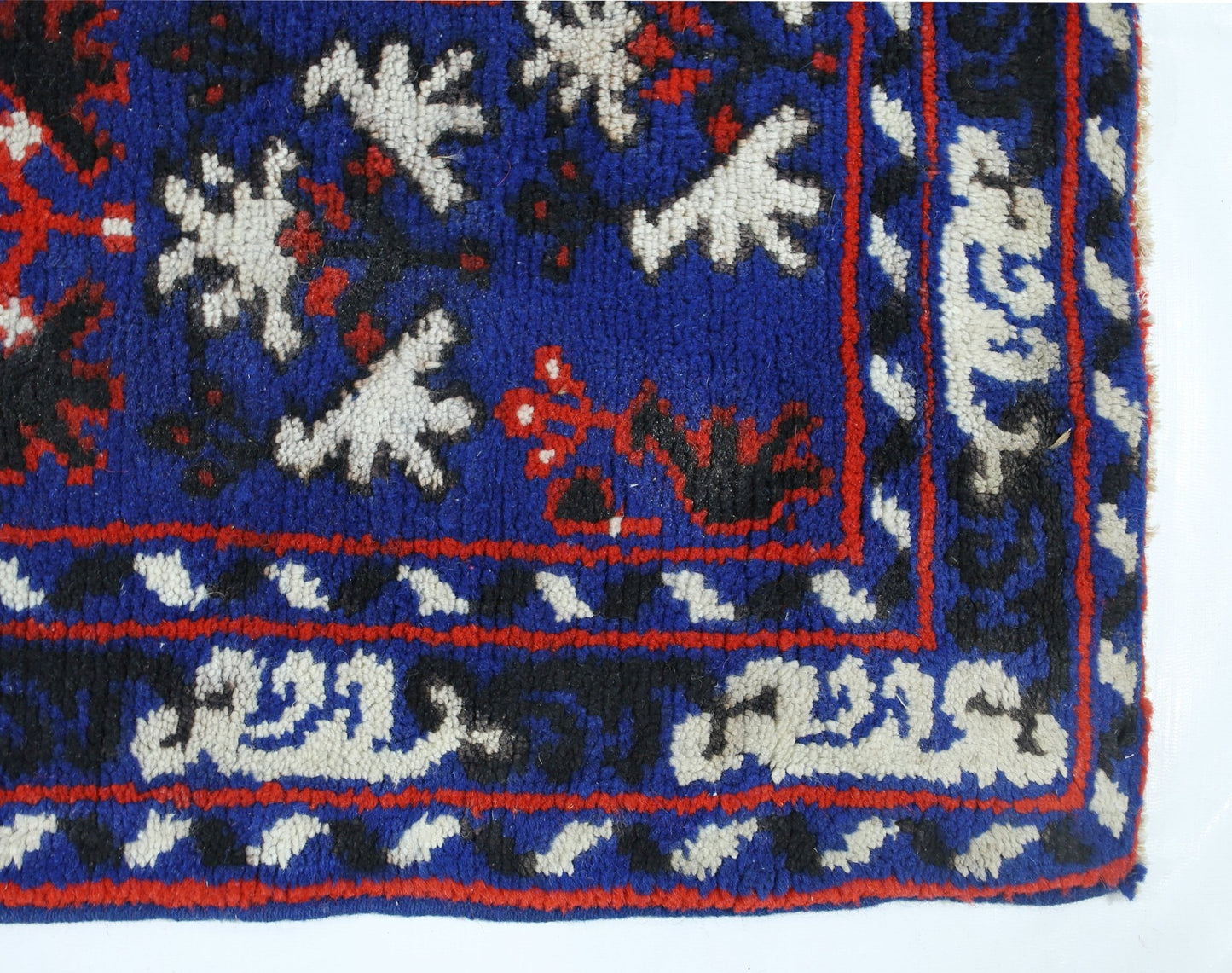 A vintage handmade Turkish wool rug featuring a blue field with white and red geometric patterns.