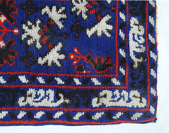 A vintage handmade Turkish wool rug featuring a blue field with white and red geometric patterns.