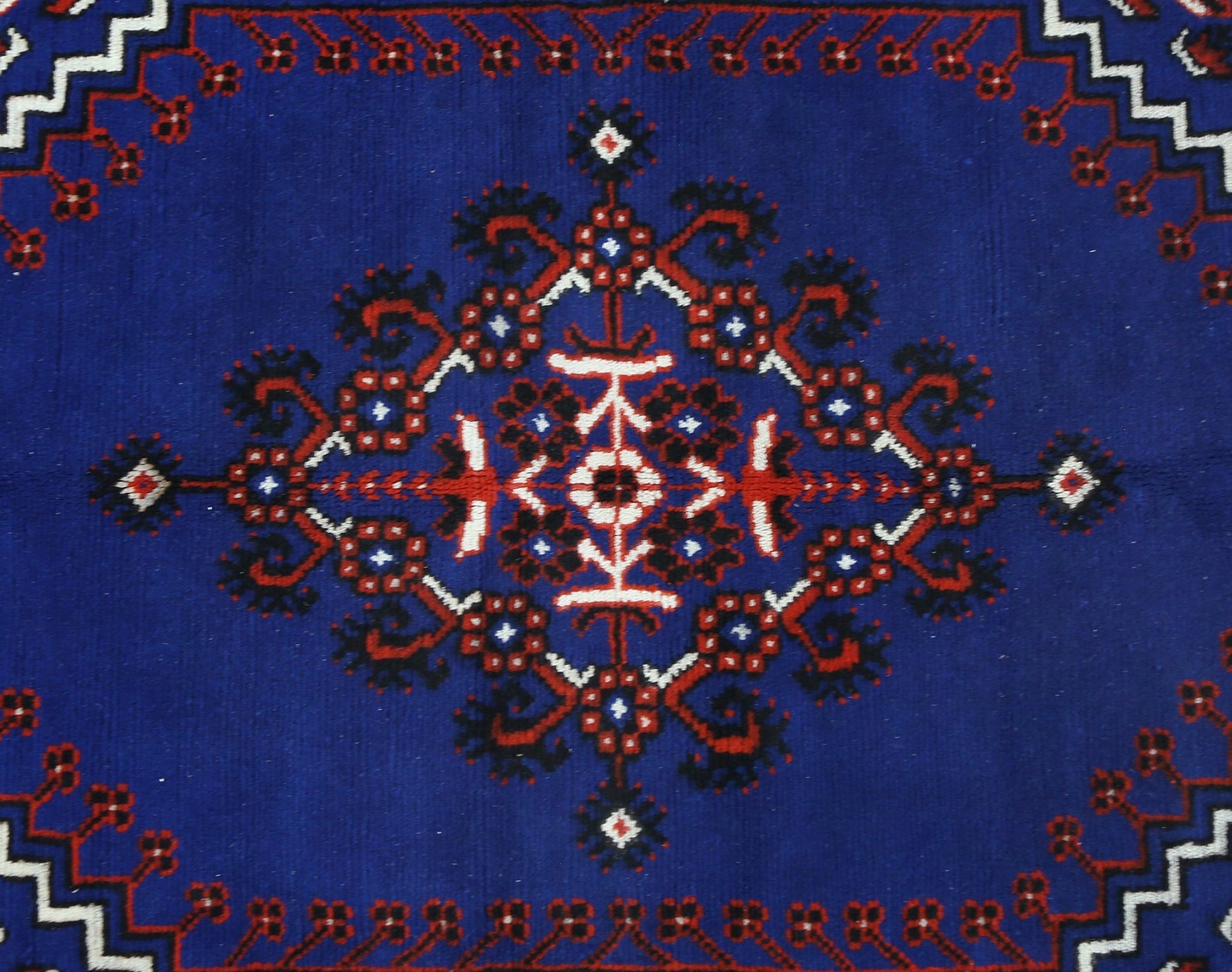 A vintage handmade Turkish rug featuring a central geometric floral medallion on a deep blue field.