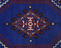 A vintage handmade Turkish rug featuring a central geometric floral medallion on a deep blue field.