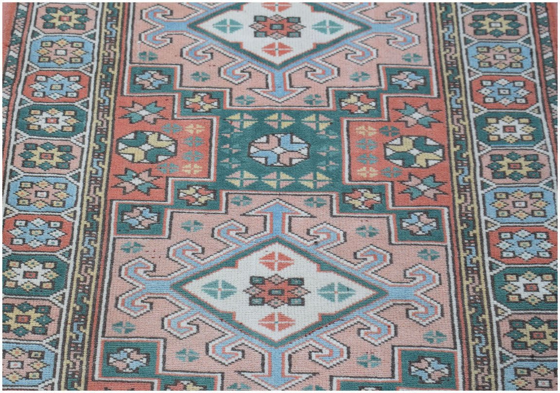 A vintage handwoven Turkish Kars runner featuring geometric patterns in pink, green, and blue.