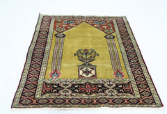A vintage handmade Turkish prayer rug featuring a mustard yellow field with floral motifs.