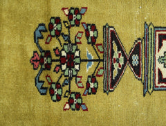 A close-up of a vintage Turkish prayer rug featuring a floral motif in a vibrant yellow field.