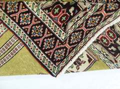 A vintage handmade Turkish prayer rug featuring a geometric floral border and a green field.