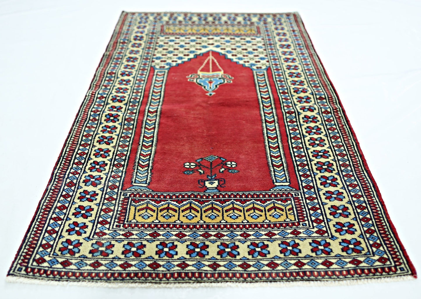 A handmade vintage Turkish Kayseri prayer rug featuring a red field with floral and lamp motifs.