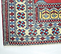 A corner view of a vintage Turkish Kayseri rug featuring geometric floral patterns in red and blue.