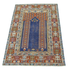 A vintage Persian prayer rug featuring a central blue mihrab design on a rust-colored field.