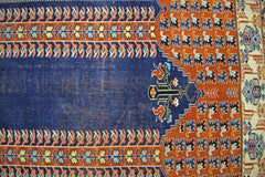 A vintage Persian prayer rug featuring a blue mihrab design with intricate floral and geometric motifs.