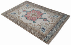 A vintage handwoven Turkish rug featuring a central pink floral medallion on a cream background.