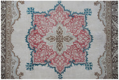 A vintage handwoven Turkish rug featuring a central floral medallion in red, teal, and brown.