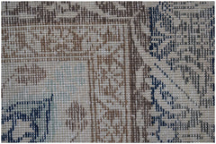 A close-up of a handwoven vintage Turkish rug featuring a geometric pattern in blue and brown.