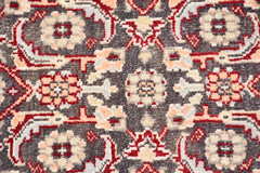 A close-up of a vintage Turkish runner featuring a geometric floral pattern in red, cream, and grey.