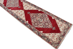 A vintage handmade Turkish runner rug featuring a red field with geometric medallions in wool.